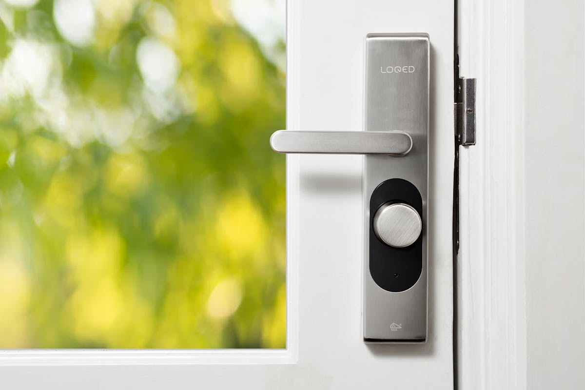 Sleek smart door lock with biometric reader on a white door