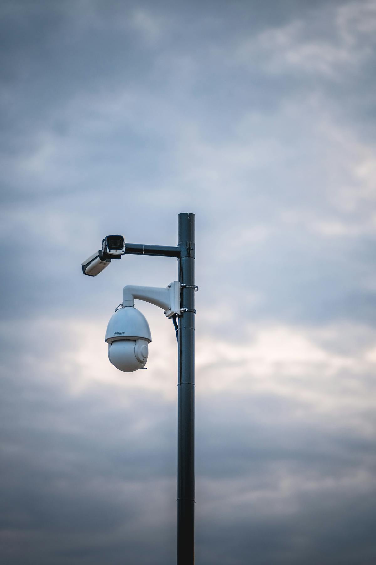 Dual Dahua CCTV cameras on a pole against a dramatic cloudy sky