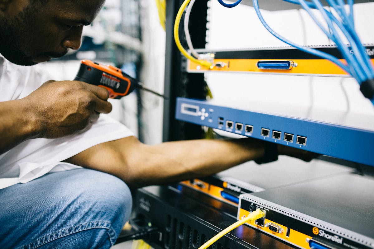 Black network engineer configuring equipment in a live server rack